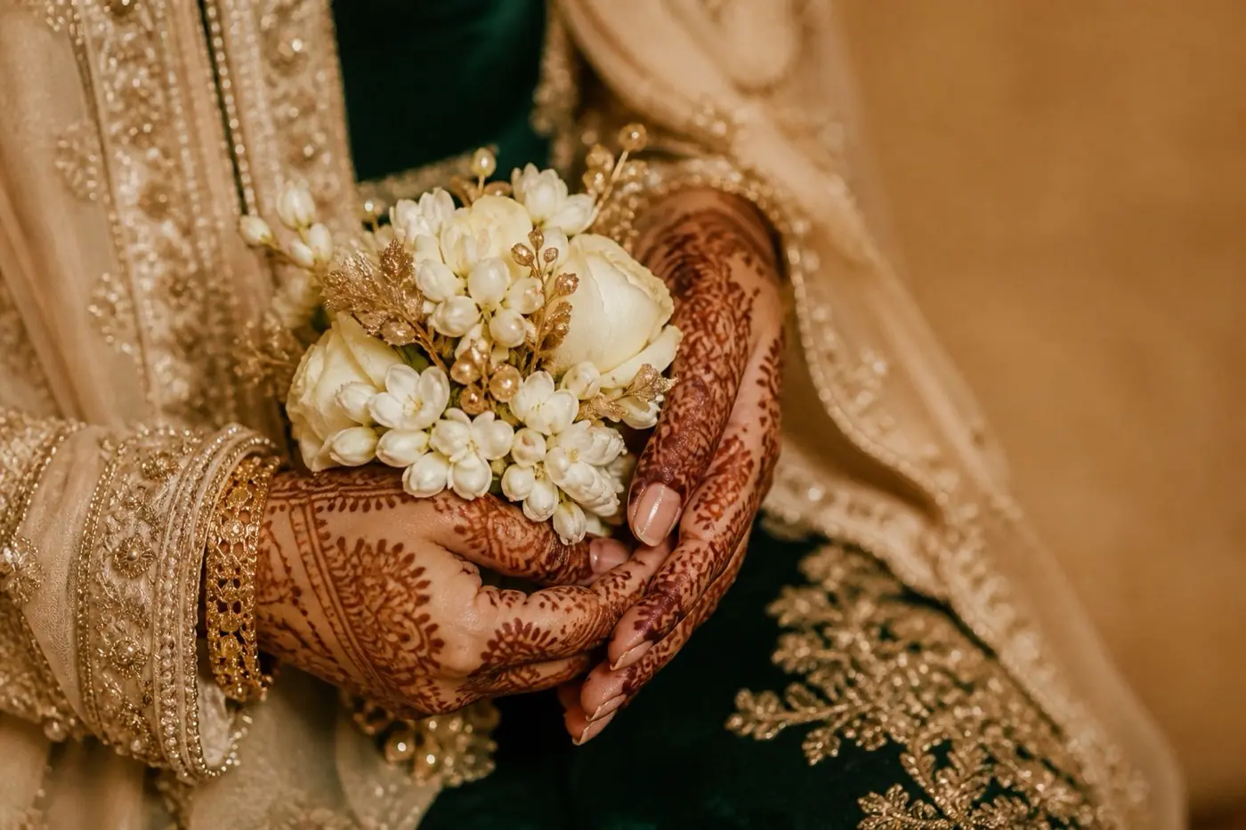 A bride's mehndi hands holding flowers